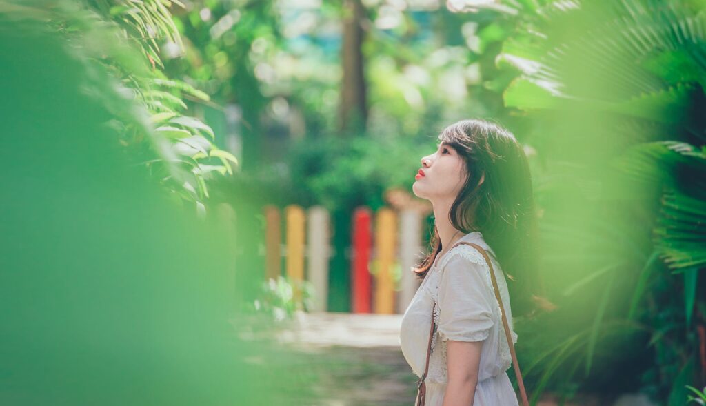 Portrait of a young woman enjoying leisure time in a vibrant green park setting.