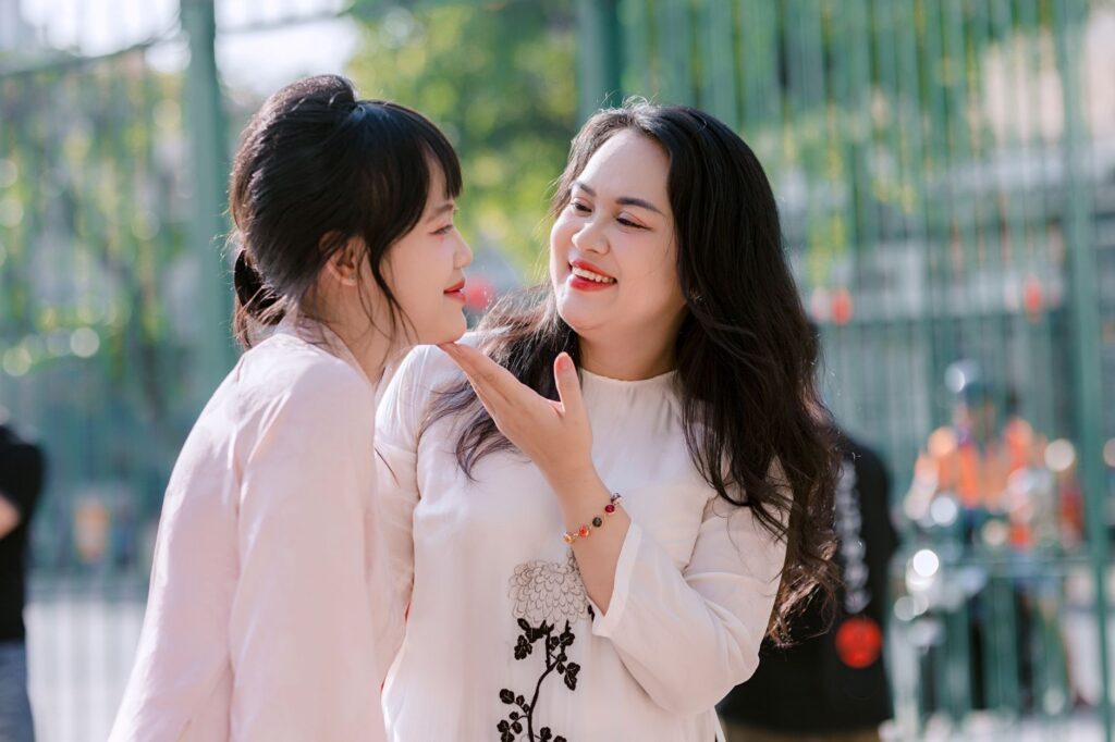Two smiling women enjoying a bright, sunny day outdoors, sharing a joyful moment.