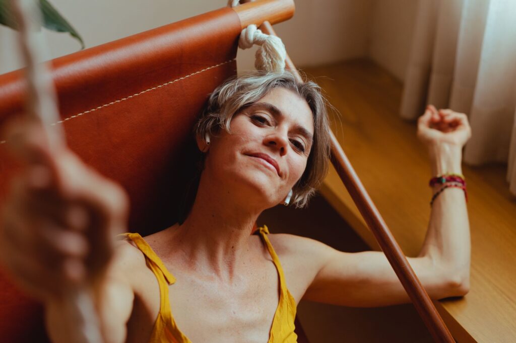 A senior woman relaxes on a hammock indoors, embodying calm and contentment.