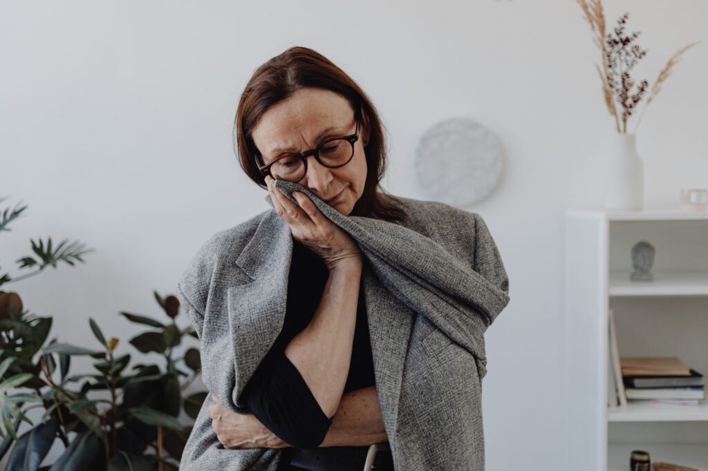 A woman expressing sadness in a quiet indoor setting, surrounded by plants.