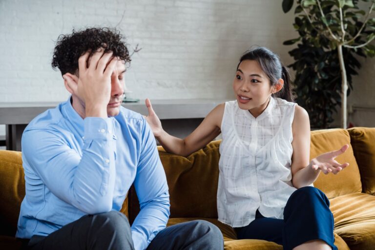 A couple having a serious conversation while sitting on a couch indoors.